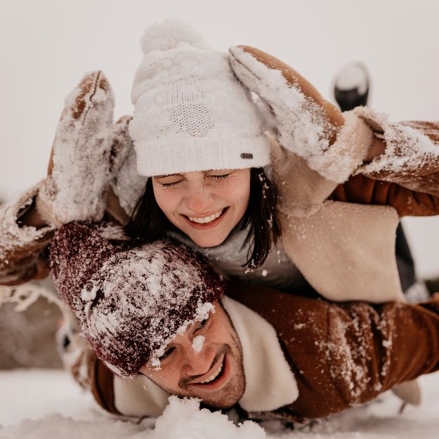 couple allongé dans la neige qui rient